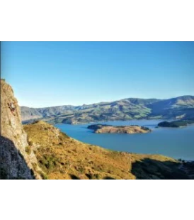 Lyttelton Harbour including Quail island and a person climbing on the rocks to the left